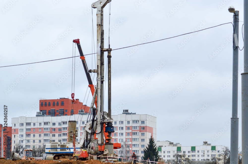 A large powerful iron pile driver, an industrial construction machine designed for lifting, installing piles at the point of immersion in the ground at the construction site of buildings and houses