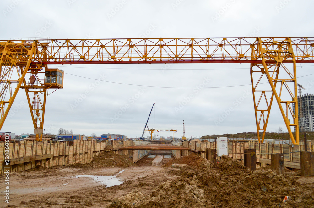 A construction site with specialized professional equipment and cranes during the construction of a modern line of the underground metro station in the big city of the metropolis