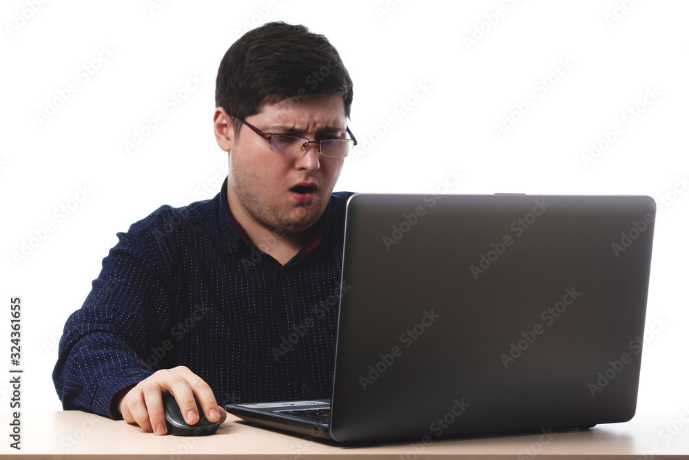 Young guy in a dark blue shirt behind a laptop in glasses for office, business vision on a white background. isolate. copy space Young guy in a dark blue shirt behind a laptop in glasses for office, business vision on a white background. isolate. copy space