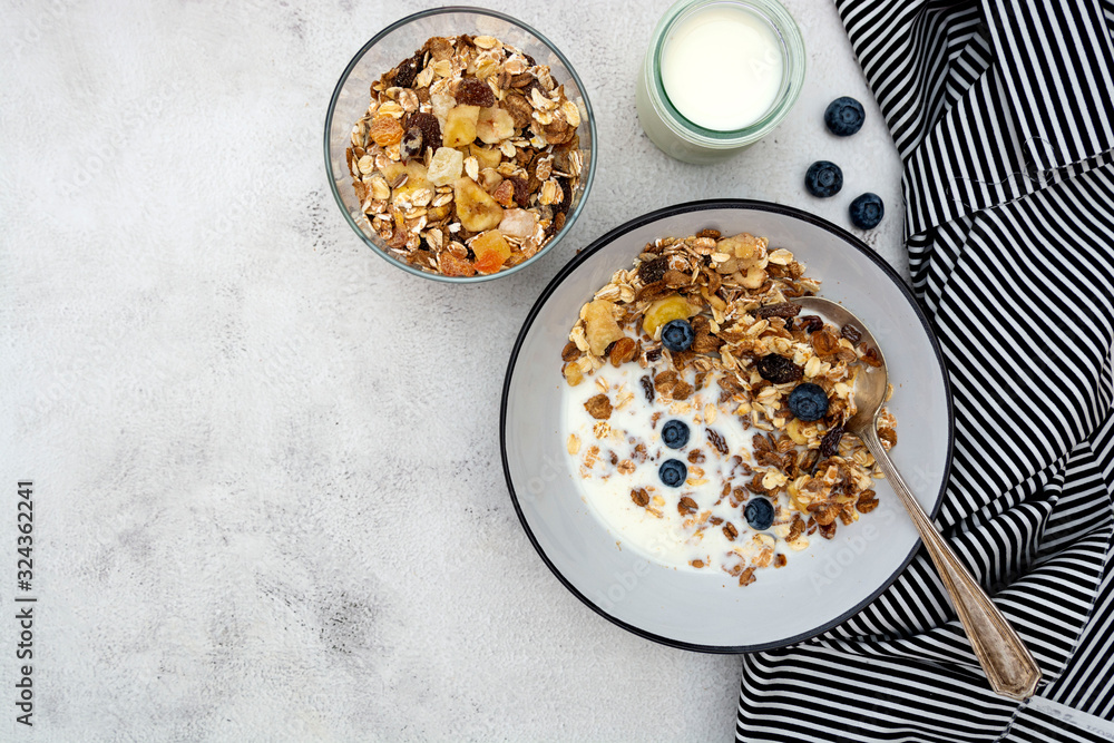 Bowl of oatmeal cereal. Whole oats, granola with dried fruit and blueberry, milk and honey. Healthy food breakfast. Copy space.
