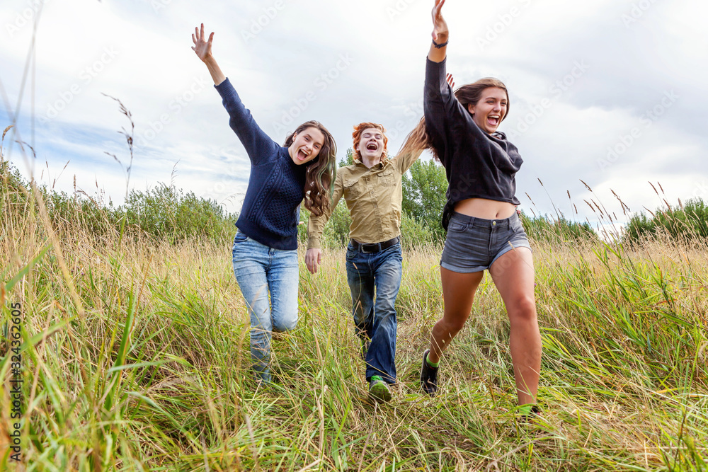 Summer holidays vacation happy people concept. Group of three friends boy and two girls running and having fun together outdoors. Picnic with friends on road trip in nature. Summer holidays vacation happy people concept. Group of three friends boy and two girls running and having fun together outdoors. Picnic with friends on road trip in nature.