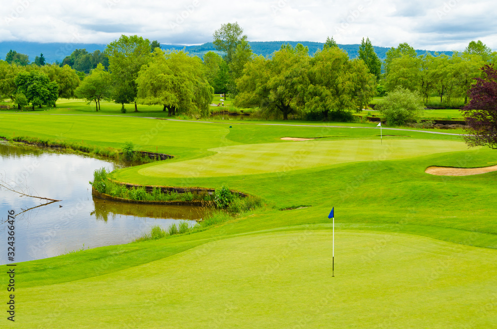 Fototapeta premium Golf course with gorgeous green and pond.