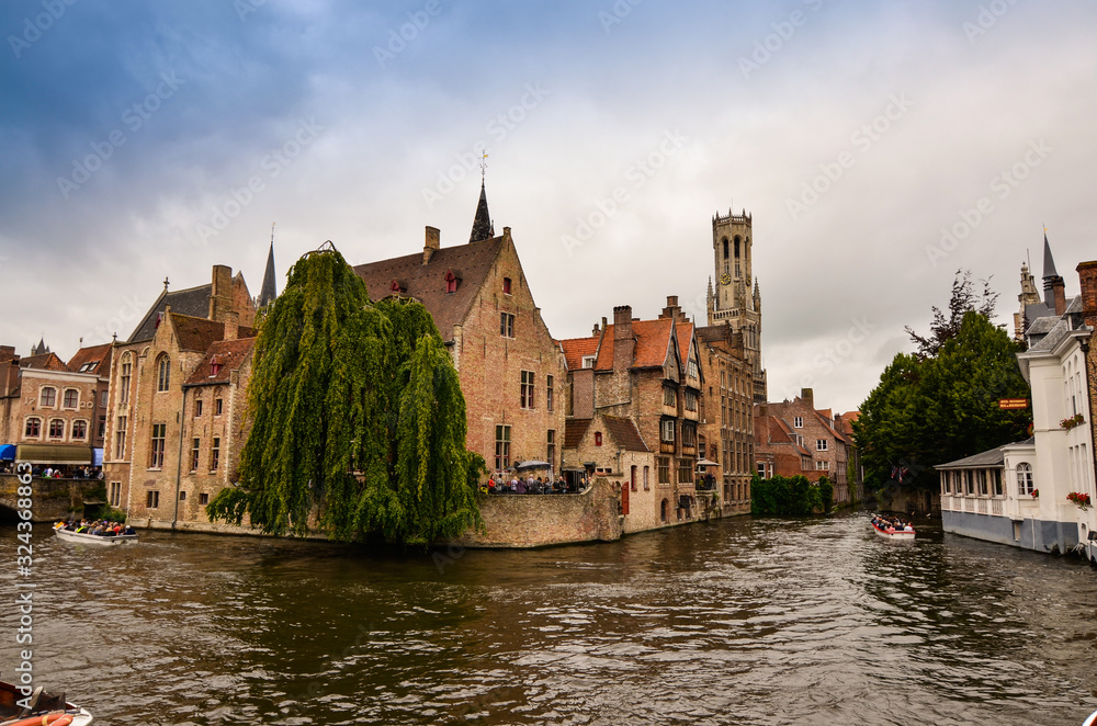 Fototapeta premium Bruges, flanders belgium.August 2019.Rozenhoedkaai is a landmark of the historic center, the most loved by tourists: the canal that curves around the house with the willow and the bell tower.