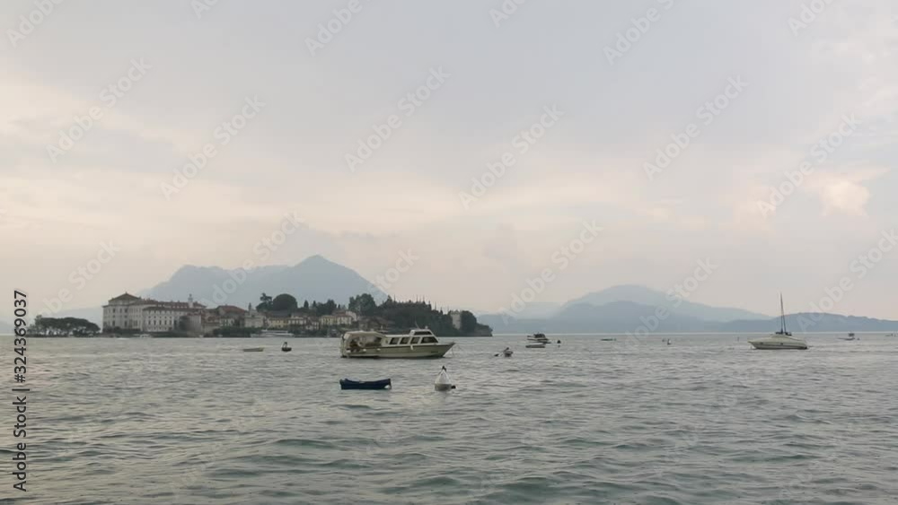 View of a ferry boat sailing in the calm waters of the Lake Maggiore in Italy. Scenic view on beautiful Lake Maggiore among the mountains, Italy View of a ferry boat sailing in the calm waters of the Lake Maggiore in Italy. Scenic view on beautiful Lake Maggiore among the mountains, Italy