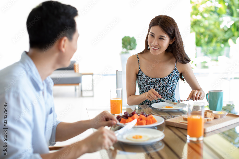 Happy young Chinese couple having breakfast in hotel room Happy young Chinese couple having breakfast in hotel room