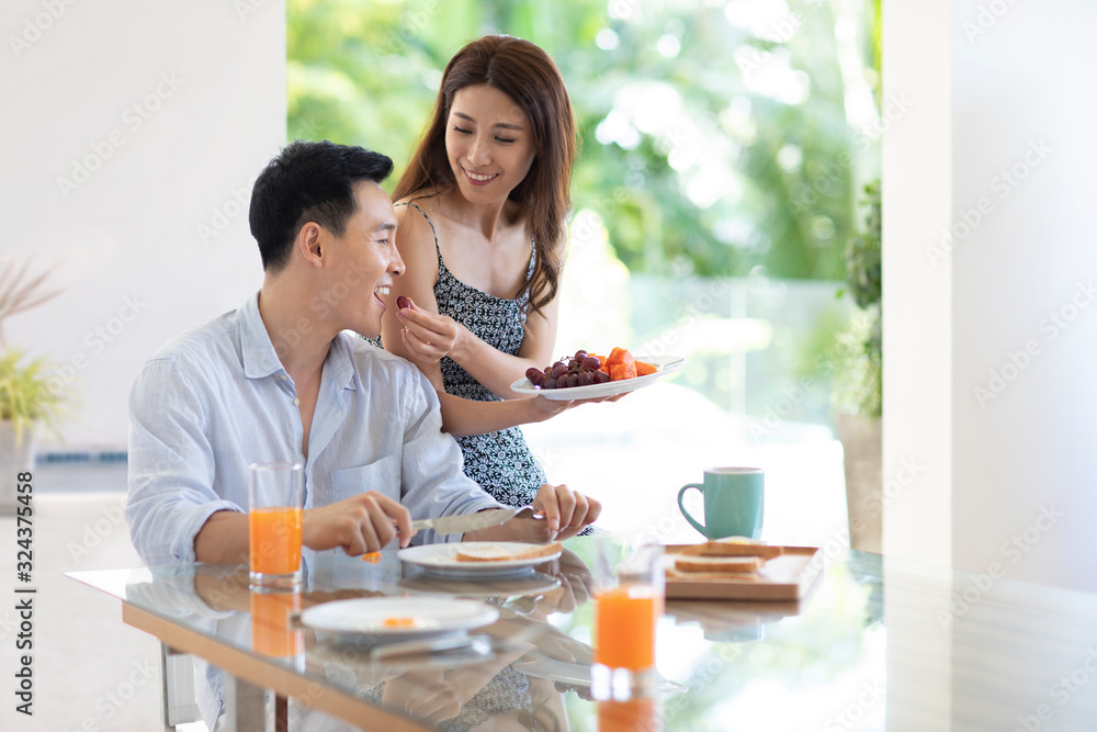 Happy young Chinese couple having breakfast in hotel room Happy young Chinese couple having breakfast in hotel room