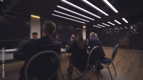 The group of people sit at the table and discuss business project. slow motion