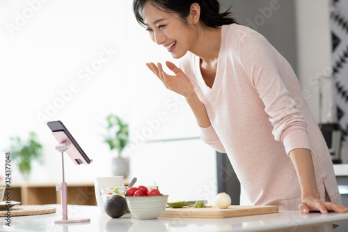 Happy young Chinese woman cooking in kitchen photo