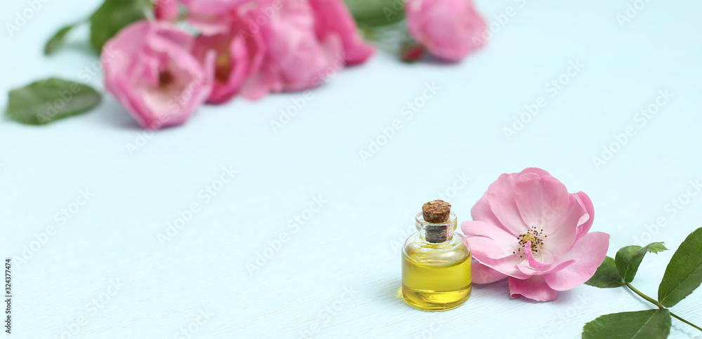 Rosehip cosmetic oil in mini bottles and pink rosehip flowers. Spa treatments for relaxation. Rosehip cosmetic oil in mini bottles and pink rosehip flowers. Spa treatments for relaxation.