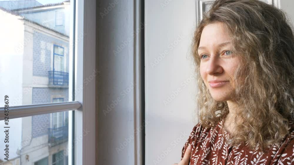 happy woman enjoys cityscape from inn room leaning on window happy woman enjoys cityscape from inn room leaning on window