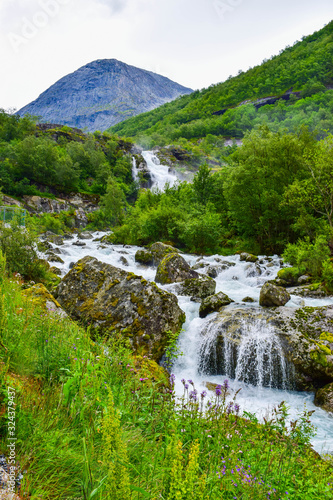 Waterfall and river which is located near path to the Briksdalsbreen (Briksdal) glacier. The melting of this glacier forms waterfall and river with clear water. Jostedalsbreen National Park. Norway. photo