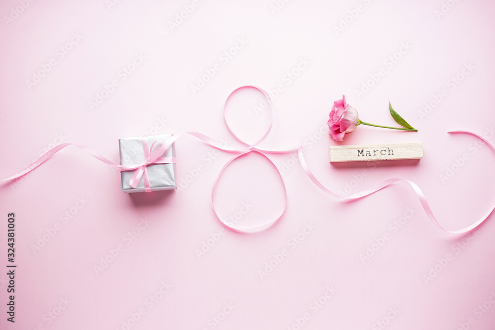 Womens day on March 8th concept. Eustoma flower with gift box and ribbon on a pink pastel background. Flat lay
