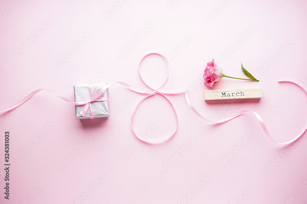 Womens day on March 8th concept. Eustoma flower with gift box and ribbon on a pink pastel background. Flat lay Womens day on March 8th concept. Eustoma flower with gift box and ribbon on a pink pastel background. Flat lay