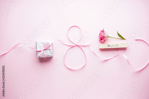 Womens day on March 8th concept. Eustoma flower with gift box and ribbon on a pink pastel background. Flat lay