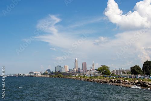Beautiful summer landscape  which depicts the rocky shore of the lake  waves on the water and in the distance are the pain of skyscrapers. View of city of Cleveland Ohio USA from the lake Erie