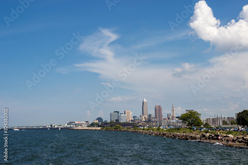 Beautiful summer landscape, which depicts the rocky shore of the lake, waves on the water and in the distance are the pain of skyscrapers. View of city of Cleveland,Ohio,USA from the lake Erie © Liudmila