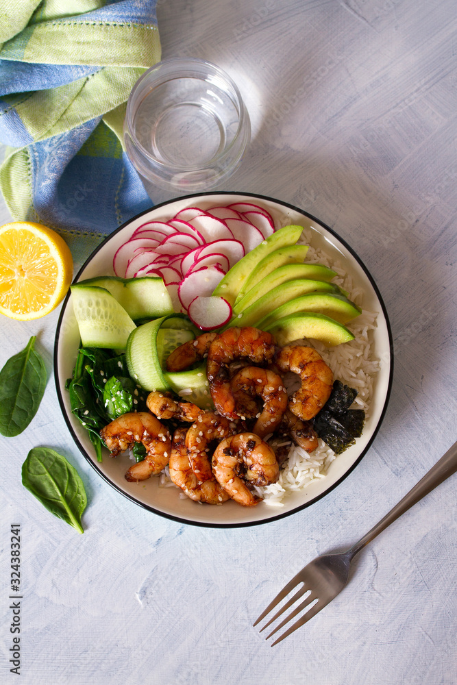 Honey soy shrimp rice bowl with spinach, radish cucumber, seaweed and avocado. View from above, top view