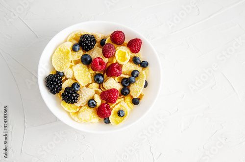 Healthy breakfast with cornflakes in a white plate, berries, milk and coffee on a white background.