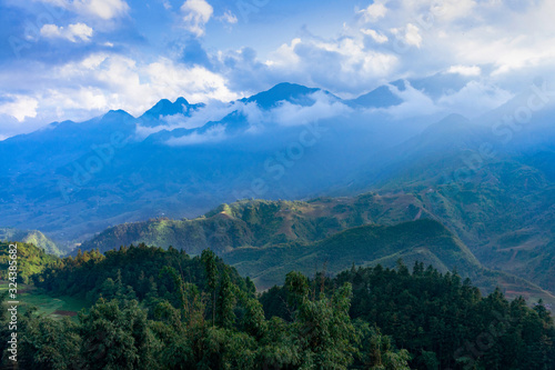 Beautiful scenery of Cat Cat village, popular tourist trekking destination. Rice field terraces. beautiful rays of the sun illuminate part of the mountain. Mountain view in the clouds. Sapa, Vietnam.