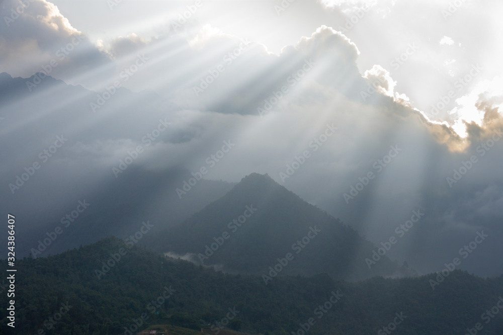rays of the sun from behind the clouds over the mountains. North Vietnam.