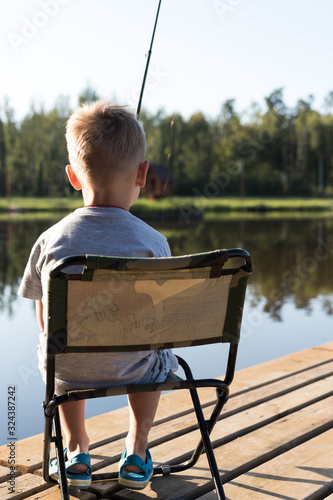 background. a boy with a fishing rod sits in a chair and catches a fish