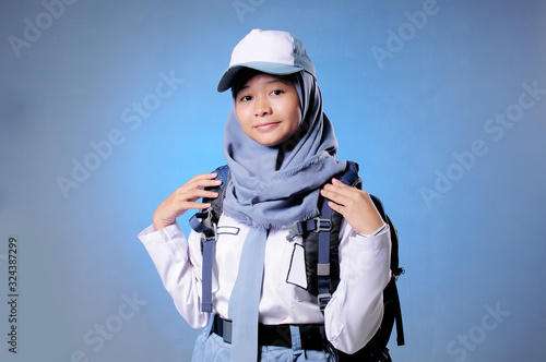 a Muslim high school student shows an expression of confidence blue background © Slamet Mulyadi