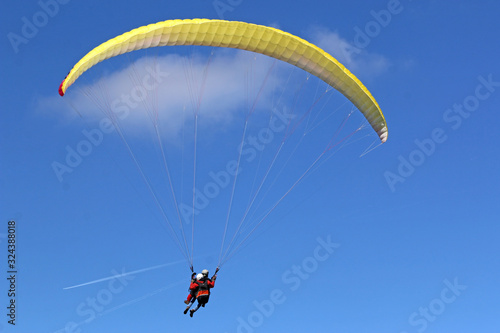 Tandem Paraglider flying wing in a blue sky 