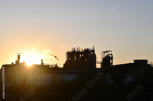 Sun peeking over factory at sunrise