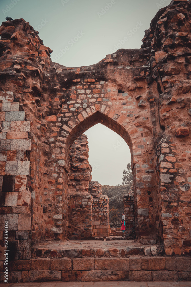 Arch in ruins. New Delhi: Qutub (Qutb) Minar, the tallest free-standing stone tower in the world, and the tallest minaret in India, constructed with red sandstone and marble in 1199 AD. 