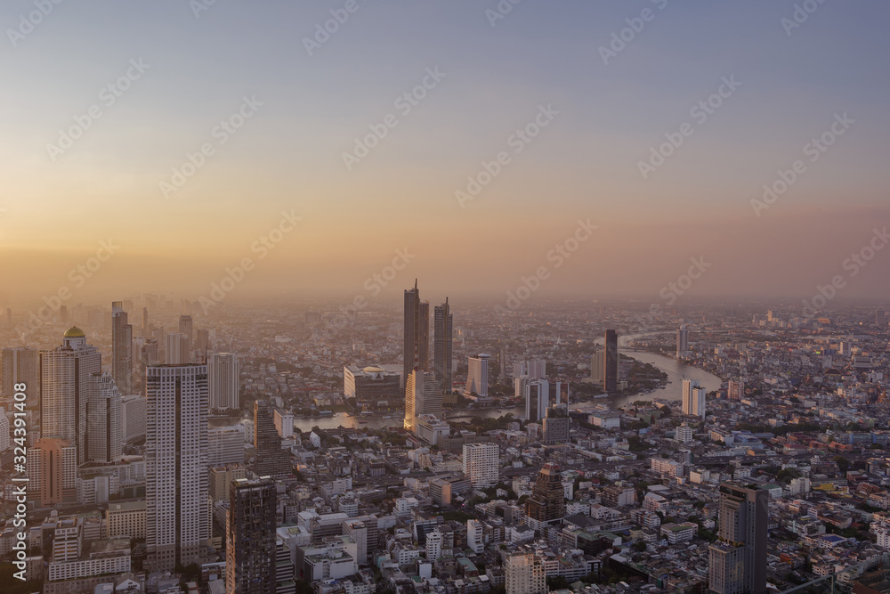Aerial view of skyline cityscape of Bangkok, buildings along Chao Phraya river, with dramatic golden, blue and purple twilight sky in sunset with air pollution of pm 2.5 dust, from Mahanakorn Tower.