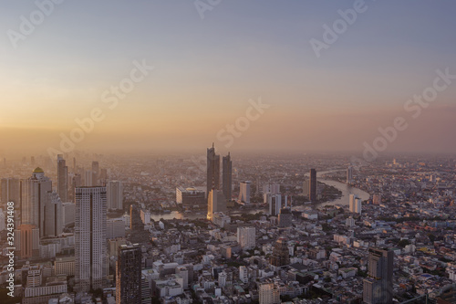 Aerial view of skyline cityscape of Bangkok  buildings along Chao Phraya river  with dramatic golden  blue and purple twilight sky in sunset with air pollution of pm 2.5 dust  from Mahanakorn Tower.