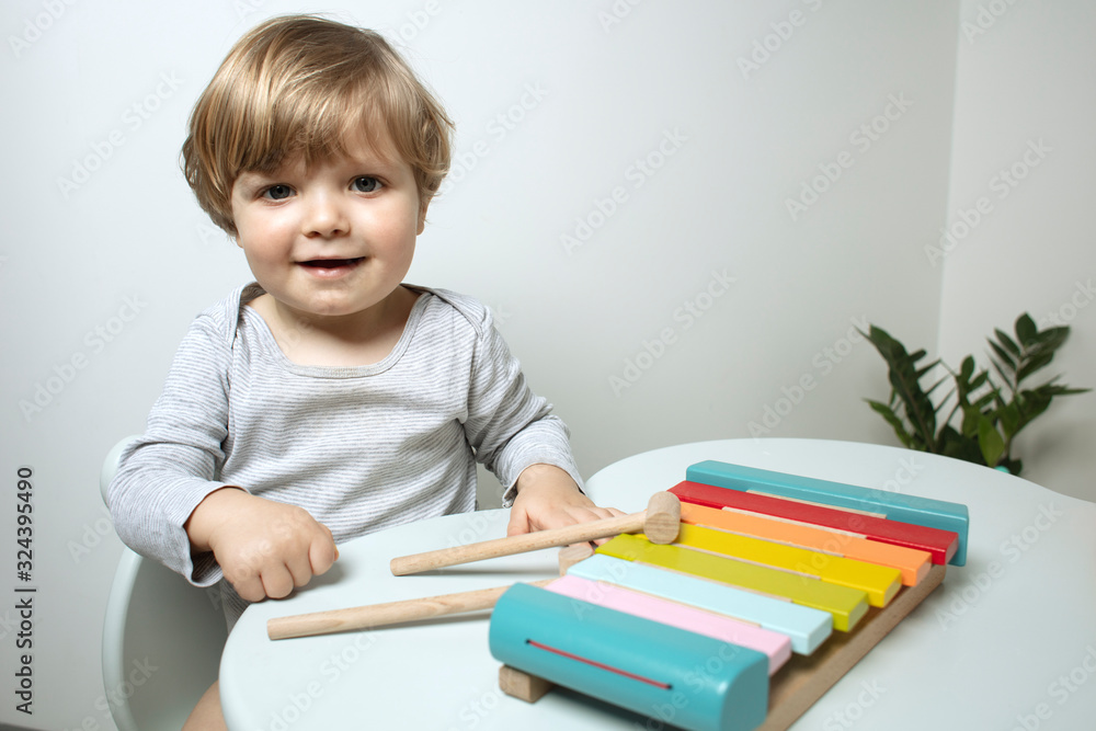 Beautiful toddler play with a xylophone toy at home. Happy child play at the table in the baby room. Child plays musical instrument. Funny baby. Play music. Lifestyle. Beautiful toddler play with a xylophone toy at home. Happy child play at the table in the baby room. Child plays musical instrument. Funny baby. Play music. Lifestyle.