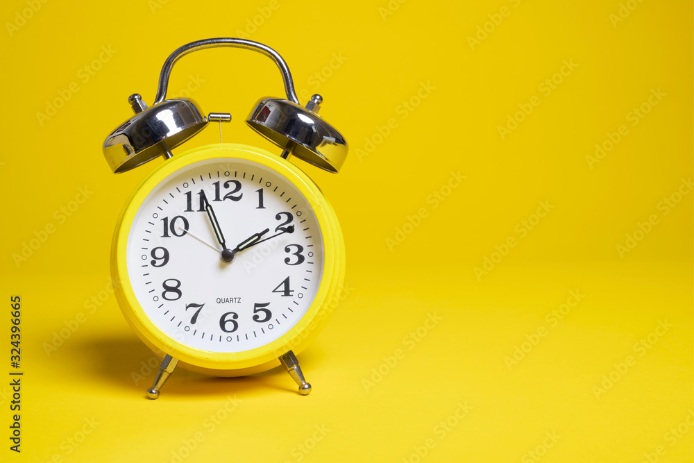 A yellow alarm clock on a yellow background A yellow alarm clock on a yellow background