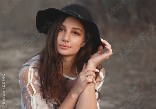 Portrait of a woman dressed in a beautiful light dress with floral print and hat, in nature.
