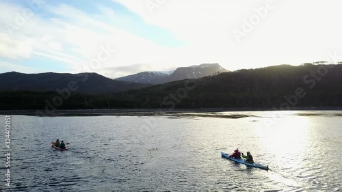 Group of Kayaks paddling on adventure coast of strait of magellan in chile into sunset