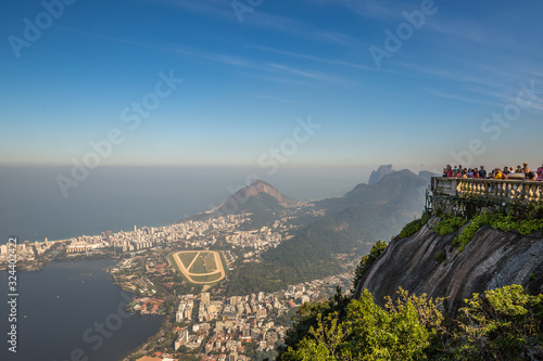 Tourists enjoying aerial view from Christ the Redeemer overlooking Rio with views of Gavea, Leblon & Jockey Club Brasileiro on clear sunny day with blue sky