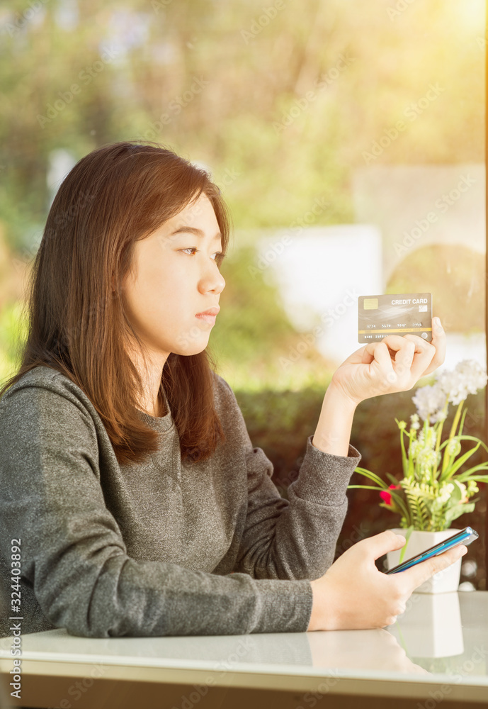 Young woman holding credit card and using smartphone