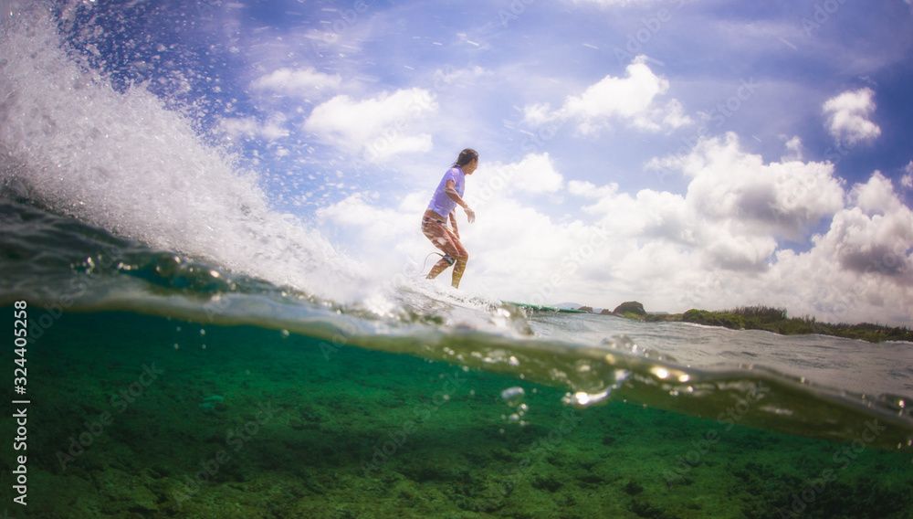 Surfer girl riding a wave over a coral reef, tropical lifestyle.