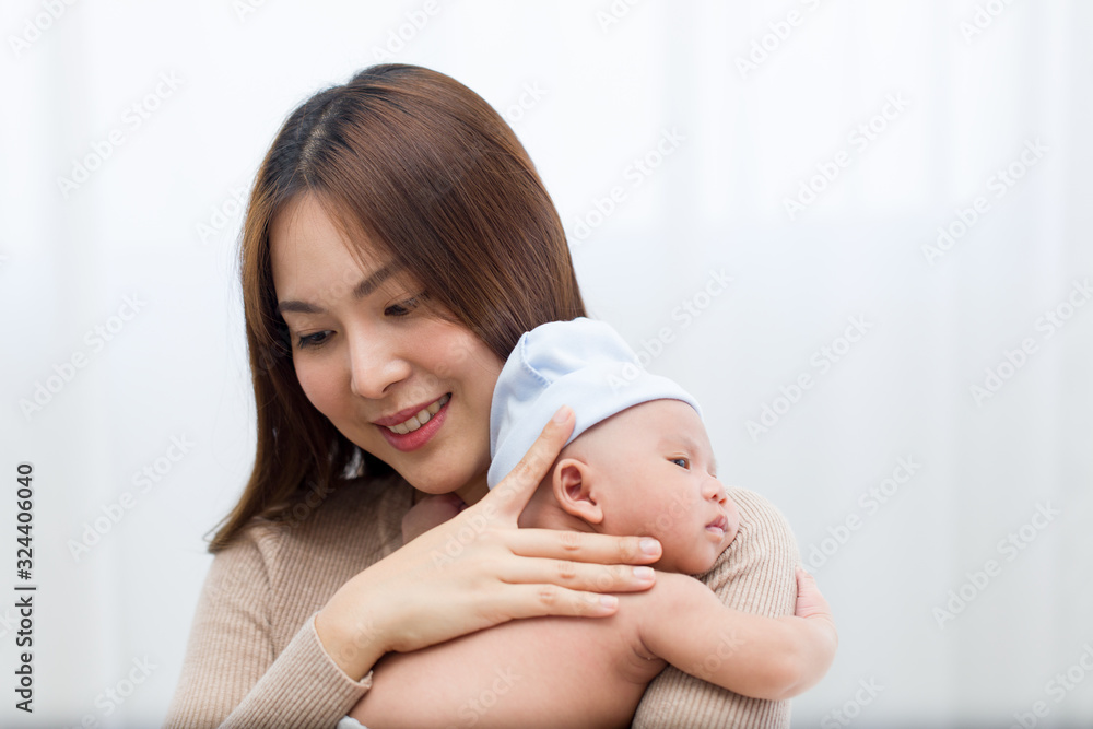 Beautiful mom holding a newborn baby and tenderly cuddles gently while the infant is sleepy on the shoulder. Asian young mother tries to lull her child to sleep with love and care. Beautiful mom holding a newborn baby and tenderly cuddles gently while the infant is sleepy on the shoulder. Asian young mother tries to lull her child to sleep with love and care.