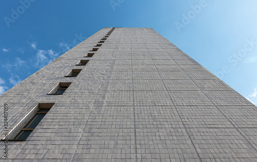 background. a tall residential building tiled with white tiles against a blue sky