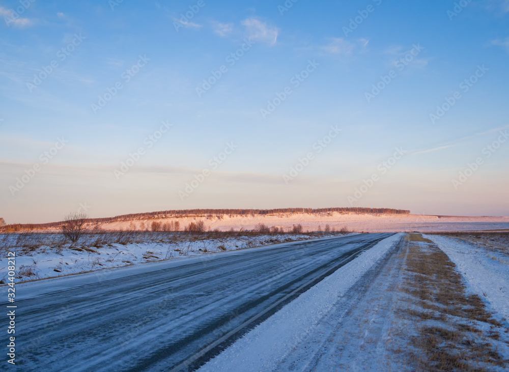 Panorama of the highway in winter Siberia. Sunrise over a snowy plain. Beautiful sky