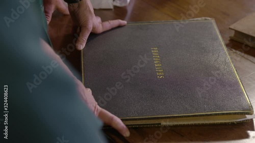 Close-up low angle tilting shot of a historic photo album  of Queen Victoria, and an attendant's hands opening the pages and pointing at the  photographs, Blair Castle, Pitlochry, Scotland photo