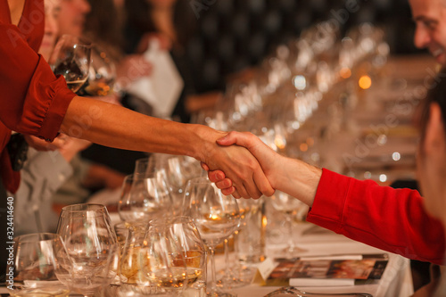 Hand shake over wine glasses