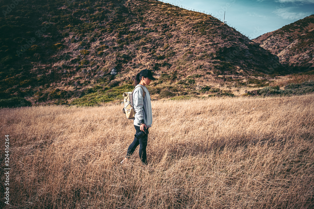 Woman photographer hiking on Makara beach, Wellington, NZ