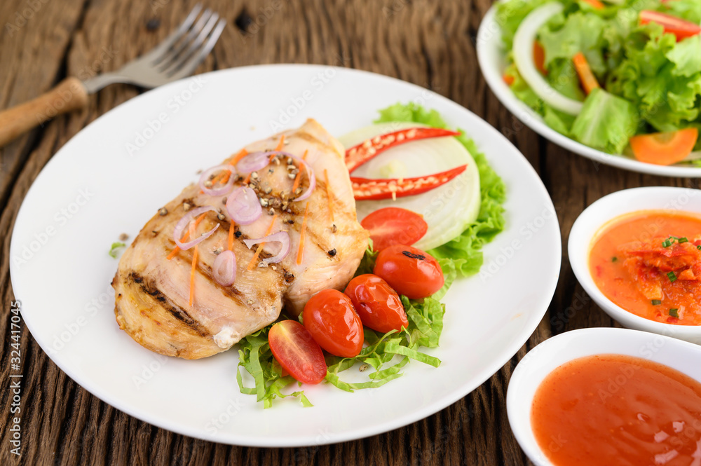 Grilled chicken on a white plate with tomatoes, salad, onion, chili and sauce. Grilled chicken on a white plate with tomatoes, salad, onion, chili and sauce.