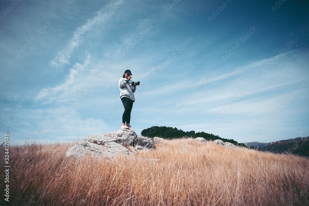 Woman photographer hiking on Makara beach, Wellington, NZ Woman photographer hiking on Makara beach, Wellington, NZ
