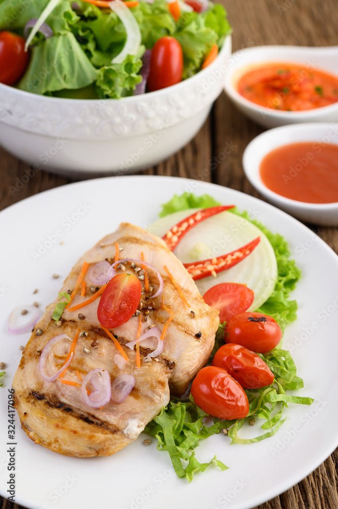 Grilled chicken on a white plate with tomatoes, salad, onion, chili and sauce.