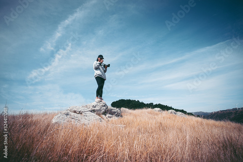 Woman photographer hiking on Makara beach, Wellington, NZ