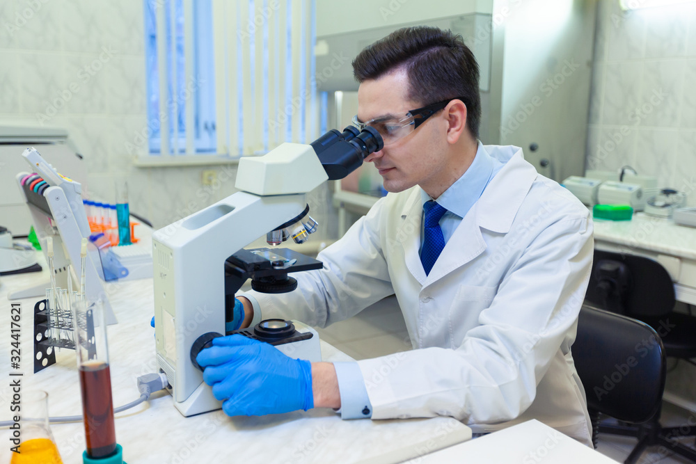 Scientist carries out scientific research looking through microscope in a medical laboratory. Scientist carries out scientific research looking through microscope in a medical laboratory.