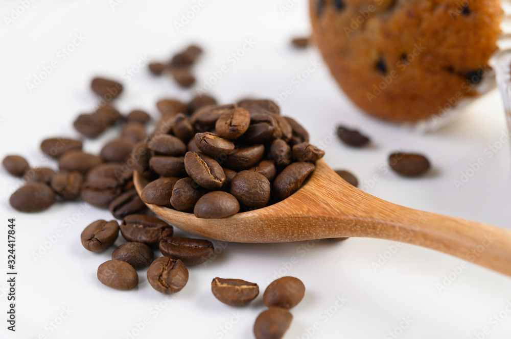 Obraz premium Coffee beans on wooden spoon and Banana Cupcakes on a white wood table.